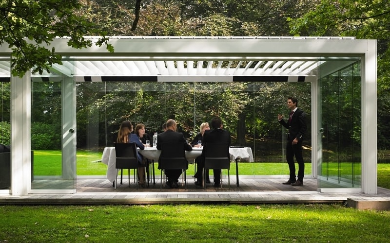 Outdoor office with glass walls, louvered roof and heating elements.